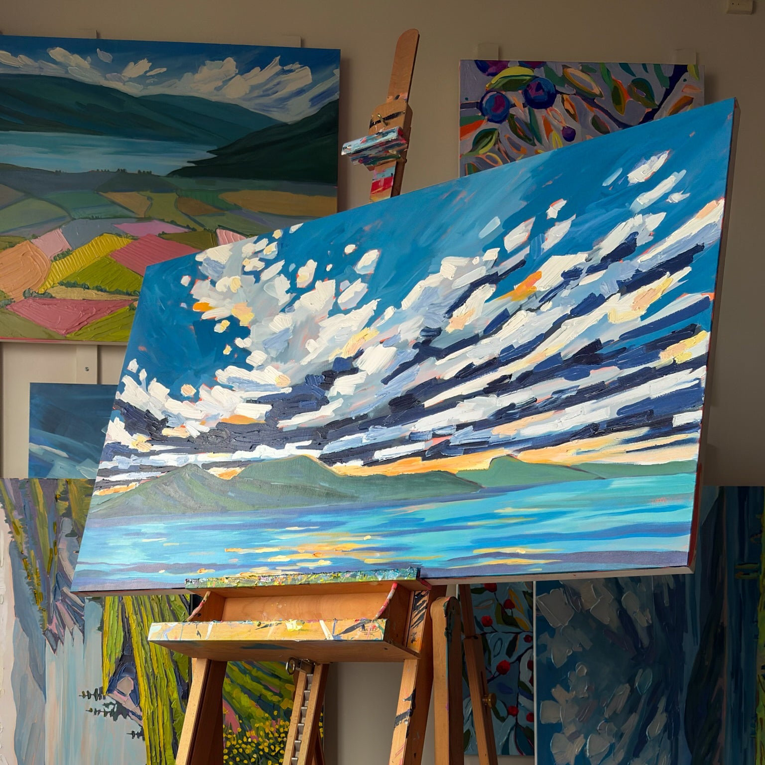 Painting on an easel in a studio with other artworks in the background